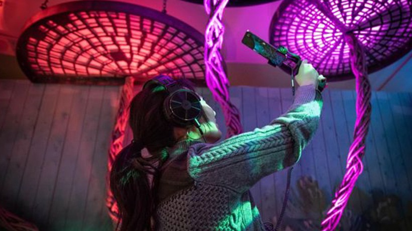 Woman holding phone device surrounded by red, purple art